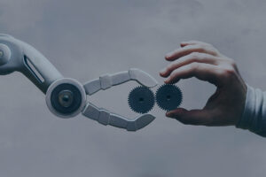 Arm eines Roboters und menschlicher Arm, die zweiZahnräder einanderhalten.