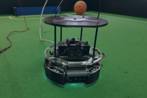 Das Titelbild des Beitrages zeigt einen Roboter, der für den größten Technik-Schülerwettbewerb RoboCupJunior entwikelt wurde und dort im Bereich "Soccer" antritt. Entwickelt wurde der Roboter von Schüler:innen des Lessing Gymnasiums in Neu-Ulm.