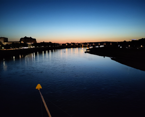 Das Bild zeigt die Elbe in Dresden am späten Abend. Am Hotizont ist noch ein kleines Stück des Sonnenuntergangs zu sehen.